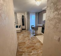 The apartment has shiny tiles, an elegant chandelier, and an open space with seating.