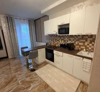 A kitchen in a 3-room apartment with glossy tiles, white cabinets, and a dining area.
