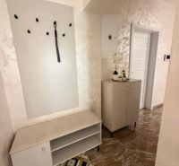 Interior with a coat rack, cabinet, and tiled floor in a 3-room apartment.