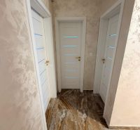 A hallway in a 3-room apartment with a tiled floor and white doors.