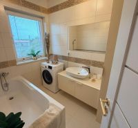 A bathroom with a bathtub, sink, and washing machine in a 3-room apartment with accessories.