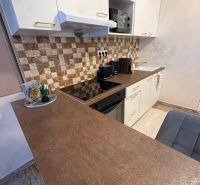 A kitchen in a 3-room apartment with a rustic countertop and tiles with a geometric pattern.