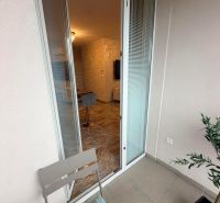 Open balcony door to a 3-room apartment with a comfortable armchair and flooring.