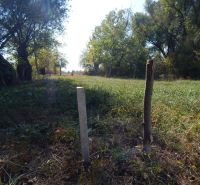 A grassy strip with wooden stakes on Recreational Land in Martovce, surrounded by trees.