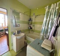 Bathroom in a two-room apartment with a bathtub, washing machine, and bathroom furniture.