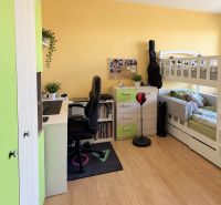 Children's room in a two-room apartment with a bed, a desk, and a floor with a wooden decor.