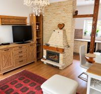 Living room with a fireplace, wood-patterned floor, carpet, chandelier, and wooden furniture.