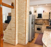 A kitchen in a 3-room apartment with a stone wall and a wooden decor floor.