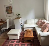 Living room in a three-room apartment with a white sofa and a red patterned carpet.