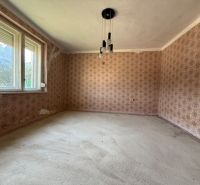 A room in a family house with floral wallpaper and large windows.
