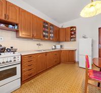 A kitchen in a family house with wooden cabinets, a stove, and a dining table.