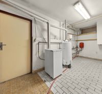 Boiler room with equipment and shelves in a family house, with piping on the tiles.