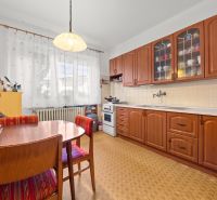 A kitchen in a family house with wooden decor furniture and curtains on the windows.