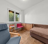 A room with a large window, a chair, a dresser, and a floor with a wooden decor in a family house.