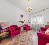 Living room in a family house with red armchairs and a table on a floor with a wooden decor.