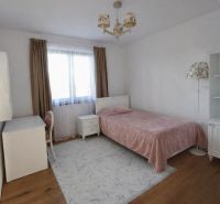 A bedroom in a family house with a bed, a desk, and a wooden decor floor.
