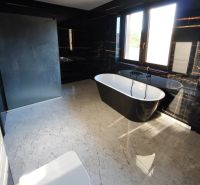 Elegant bathroom with a freestanding bathtub and black walls in a family house.