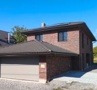 A family house in Zlaté Moravce with a brick design and a sloped roof under a blue sky.