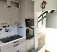 A kitchen in a family house with a built-in oven, grey cabinets, and an induction cooktop.
