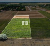 A plot for living in Nové Zámky, bordered by greenery and the surrounding countryside.
