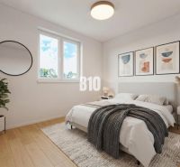 A bedroom with a bed, wood-patterned flooring, a plant, and a round mirror in a family house.