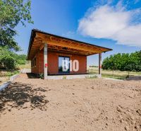 A family house in Čeľadice with an unfinished garden, surrounded by greenery and a blue sky.