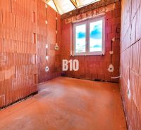 A newly built family house in Čeľadice with exposed brick walls and a plastic window.