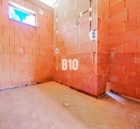 An unplastered room in a family house with red brick walls.