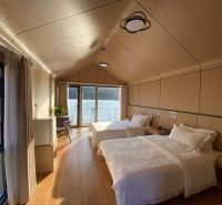 A bedroom in a cabin with two beds and a wooden decor floor, overlooking a lake.