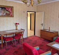 Living room with floral decor in a family house, red armchairs, patterned carpet.