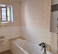 A bathroom in a family house with a bathtub, a sink, and a gas boiler.