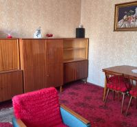Living room of a family house with retro furniture, a red carpet, and wallpapered walls.