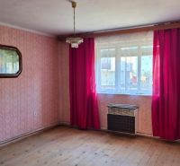 A room in a family house with pink wallpaper and a wooden decor floor.