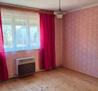 A room in a family house with wallpaper, red curtains, and a wooden decor floor.