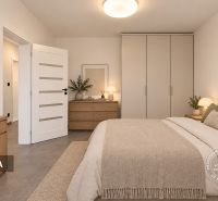 A bedroom with light furniture, a work desk, and decorations in a two-room apartment.