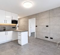 A kitchen in a 2-room apartment with white cabinets and gray tiles.