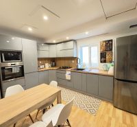 A kitchen with a wood-patterned floor, a dining table, and an elegant gray kitchen unit.