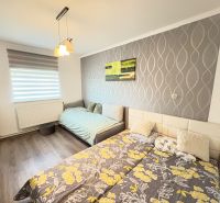 A bedroom in a family house with a wooden decor floor and patterned wallpaper on the wall.