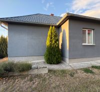 A family house in Blatné Revištia with a landscaped garden, gray facade, and hipped roof.