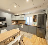 A kitchen in a family house with a wooden decor floor, white chairs, and appliances.