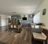 A kitchen in a family house with a wooden decor floor and a dining table.