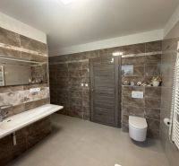 A bathroom in a family house with a large mirror and tiles with a marble pattern.