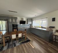 A kitchen in a family house with a wooden decor floor and a dining table.