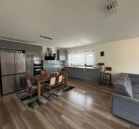 Open kitchen with a dining table and wood-patterned flooring in a family house.