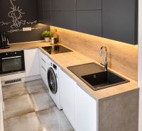 A kitchen with appliances and a wooden decor floor in a 3-room apartment.