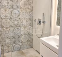 A shower corner with decorative tiles in the bathroom of a 3-room apartment.