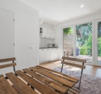 A bright room with wooden furniture and a kitchen, recreational grounds.