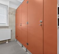 Orange stalls with doors in public restrooms in offices.