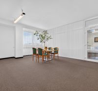 Offices with carpet, a desk and chairs, glass doors and a large window.