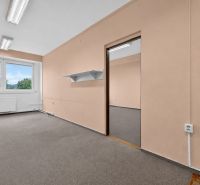 Offices with beige walls and a window with a view visible through it.